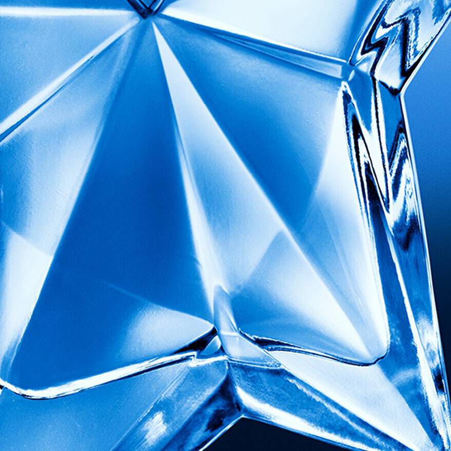 A striking blue star-shaped perfume bottle is displayed on a pedestal, surrounded by reflective surfaces and photography equipment.