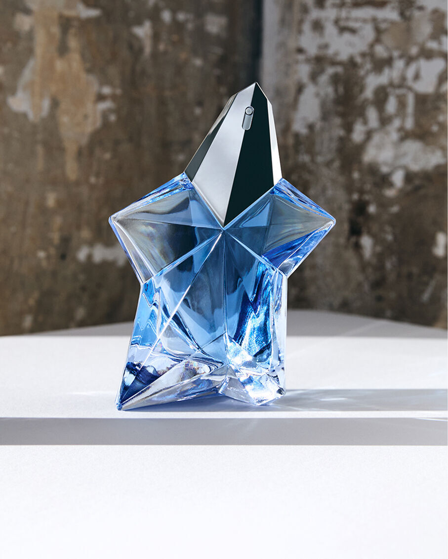 Flacon « Blue Star » de l'eau de parfum Mugler Angel pose sur une surface dans un studio.