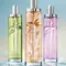 Trois flacons des nouveaux eaux de toilette Starlicious, de couleur verte, orange et rose, flottant sur l'eau, sur fond bleu
