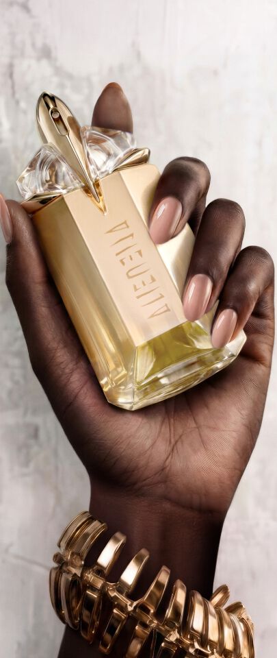 Une main feminine tenant une flacon de Mugler Alien Goddess.