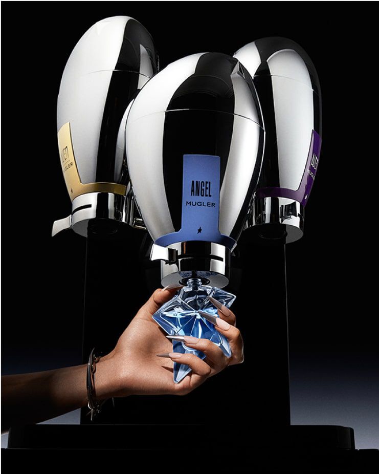 trois fontaines de parfums mugler avec au milieu une main tenant un flacon bleu angel a recharger