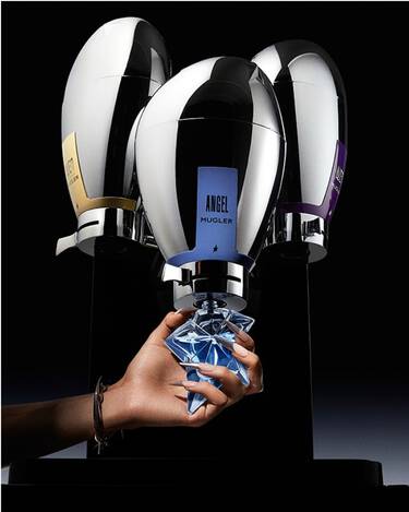 trois fontaines de parfums mugler avec au milieu une main tenant un flacon bleu angel a recharger