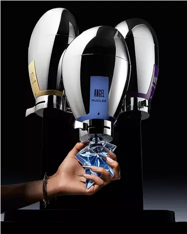 trois fontaines de parfums mugler avec au milieu une main tenant un flacon bleu angel a recharger