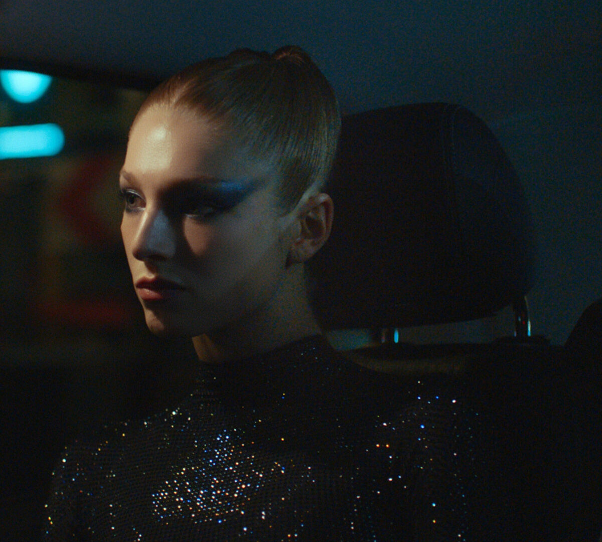 le profil d'une femme blonde avec les cheveux attaches assis dans une voiture de nuit