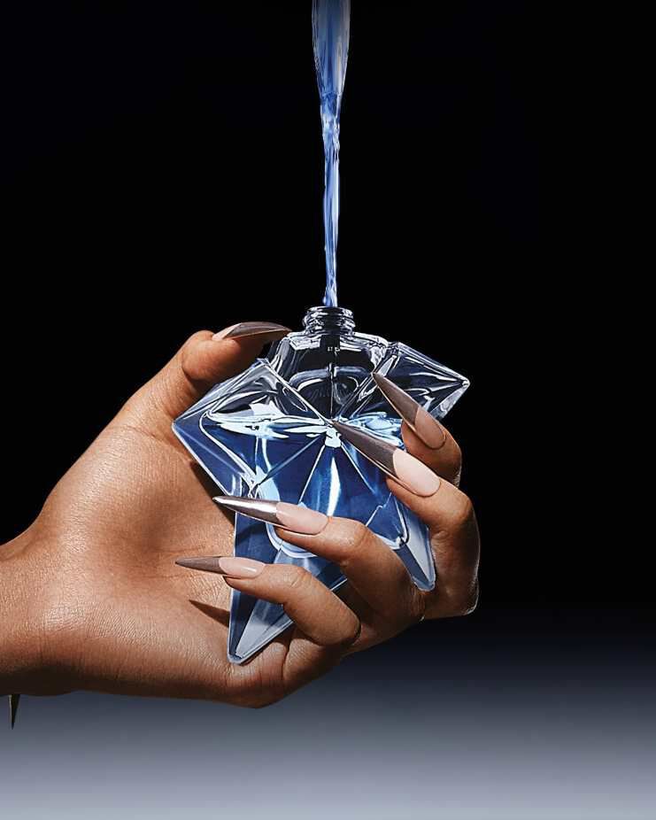 un flacon de parfum bleu angel qui est rempli par une recharge tenue dans une main