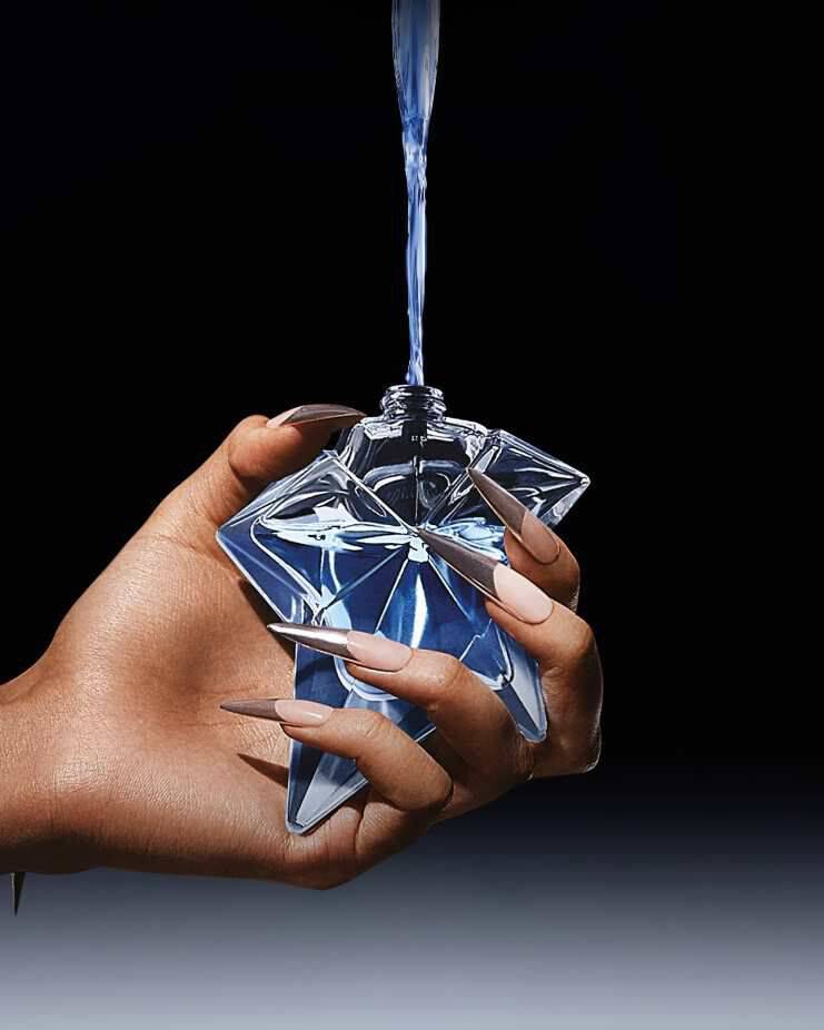 un flacon de parfum bleu angel qui est rempli par une recharge tenue dans une main