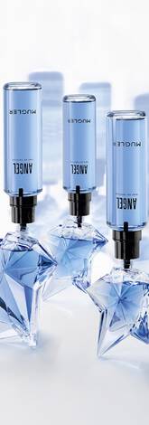 Trois flacons cylindriques bleus de recharge d eau de parfum, munis d'embouts noirs, sont inseres dans des flacons d eau de parfum transparents en forme d etoile.