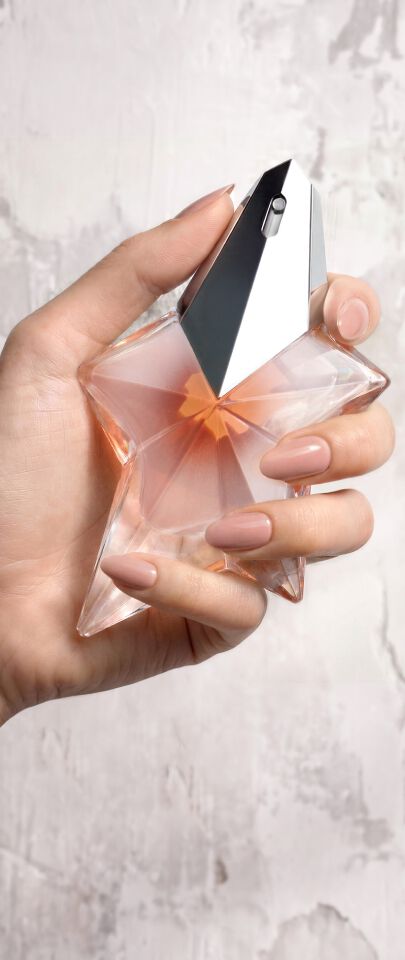 Une main feminine tenant une flacon de Mugler Angel Blush