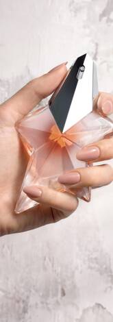 Une main feminine tenant une flacon de Mugler Angel Blush