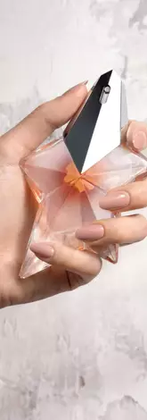Une main feminine tenant une flacon de Mugler Angel Blush