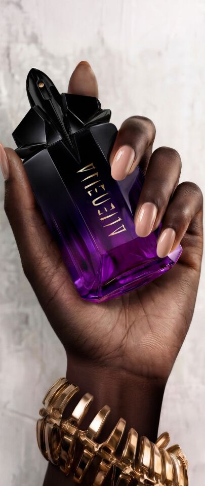 Une main feminine tenant une flacon de Mugler Alien Extraintense.