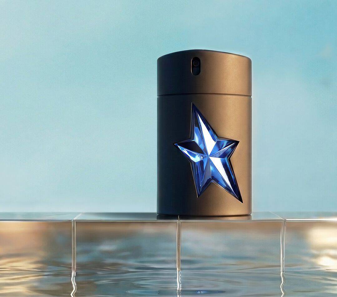 Flacon du parfum Mugler A*Men Eau de Toilette, orne d'une etoile bleue a facettes posee sur un rebord carrele au-dessus d'un bassin aux reflets miroitants.