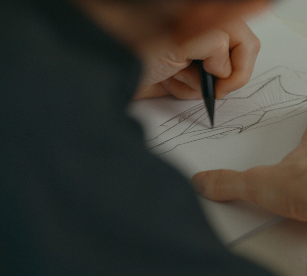 une main tenant un crayon qui dessine le croquis d'une robe sur le corps d'une femme