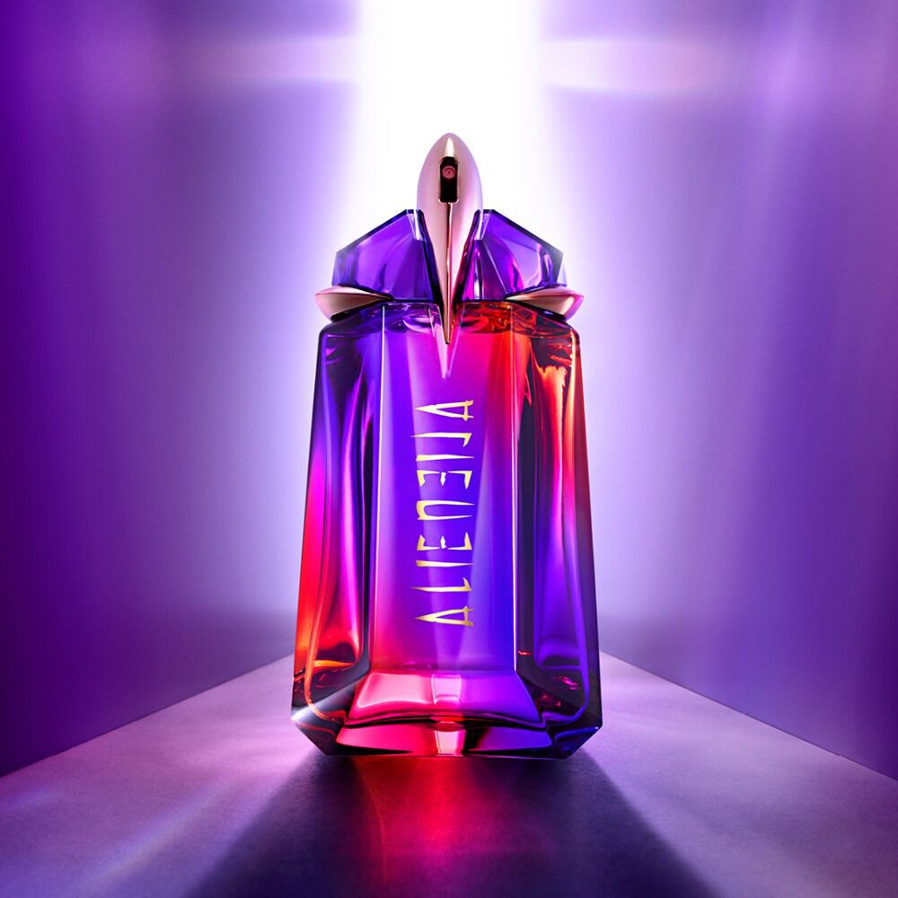 Flacon de parfum violet et rose avec un design elegant, illumine par une lumiere douce en arriere-plan.