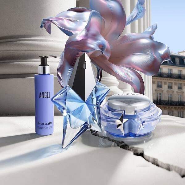 un flacon de parfum bleu un pot de creme bleu et un flacon pompe angel sur un sol carrele avec une fleur bleu a cote