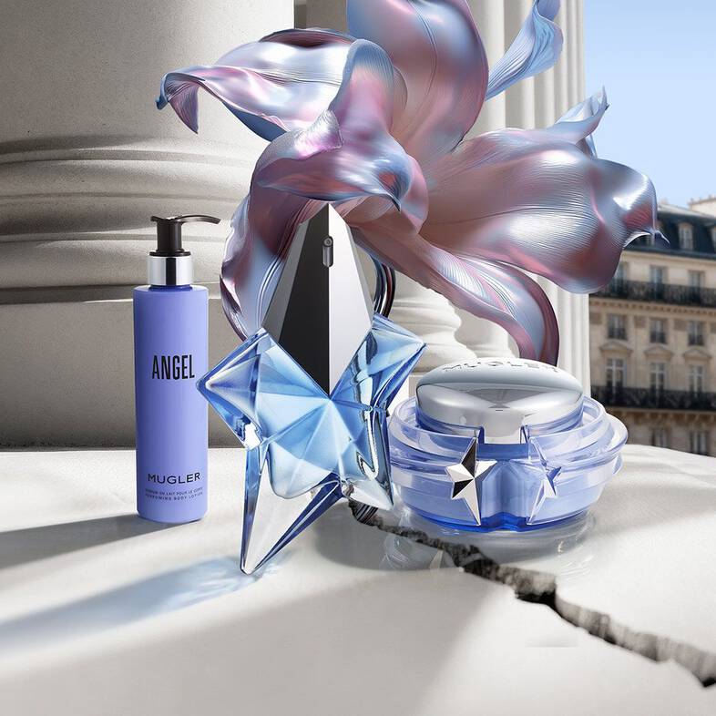 un flacon de parfum bleu un pot de creme bleu et un flacon pompe angel sur un sol carrele avec une fleur bleu a cote