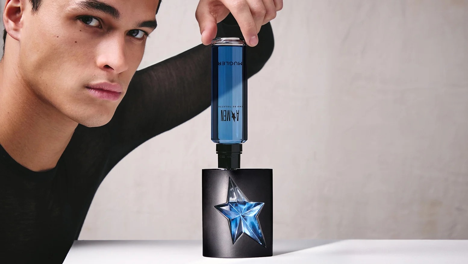 Recharge manuelle du flacon noir A*Men de Mugler avec un flacon de recharge bleu.
