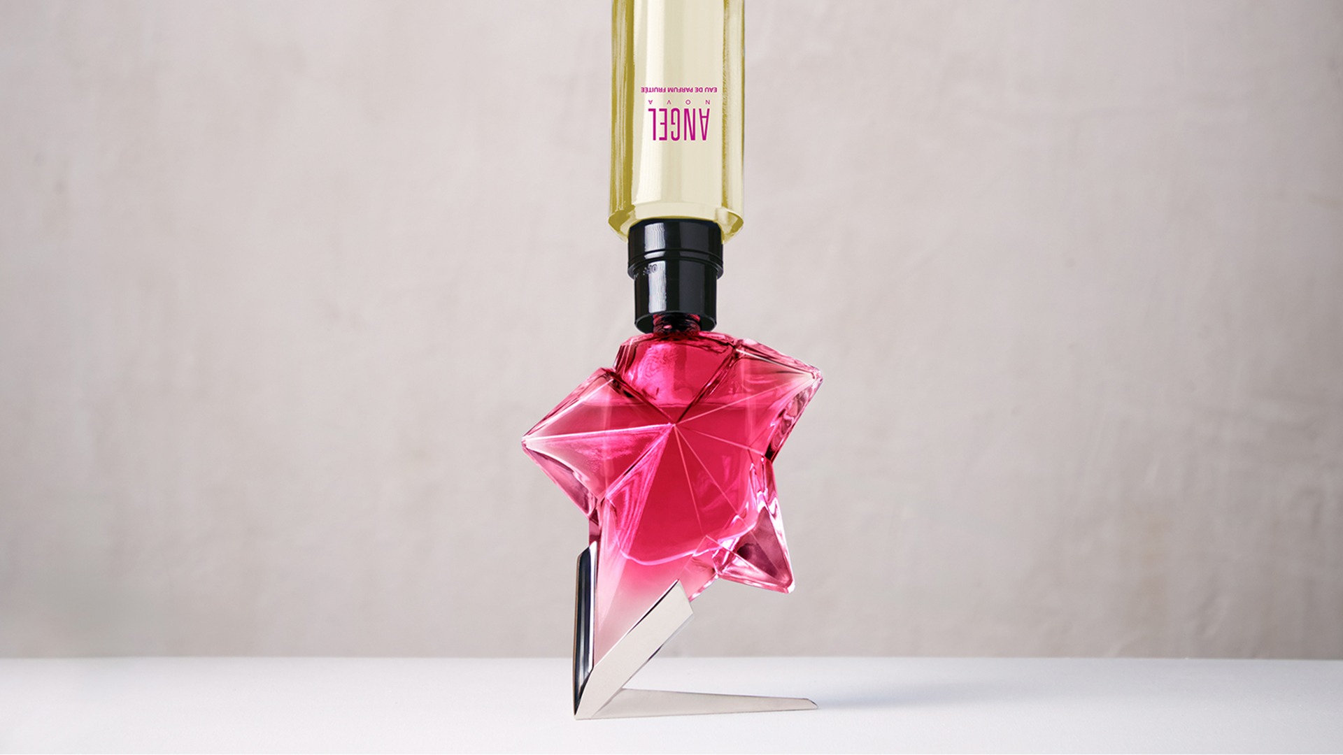 Flacon de parfum Pink Angel Nova de Mugler sur fond abstrait rouge brillant