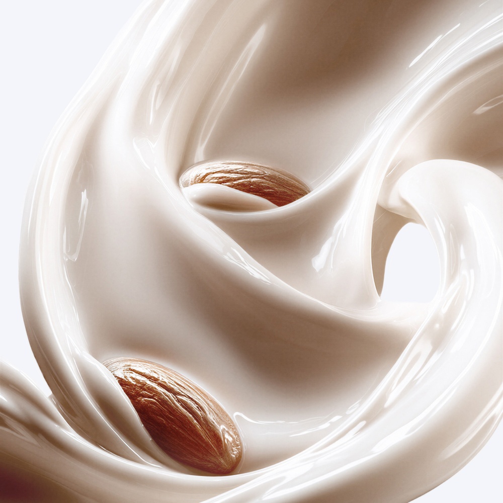 Lait d'amande crémeux avec des tourbillons élégants et des éclats de noix, évoquant une expérience raffinée.