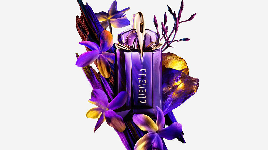 un flacon de parfum vert mugler entouré de fleurs de jasmin et de bois