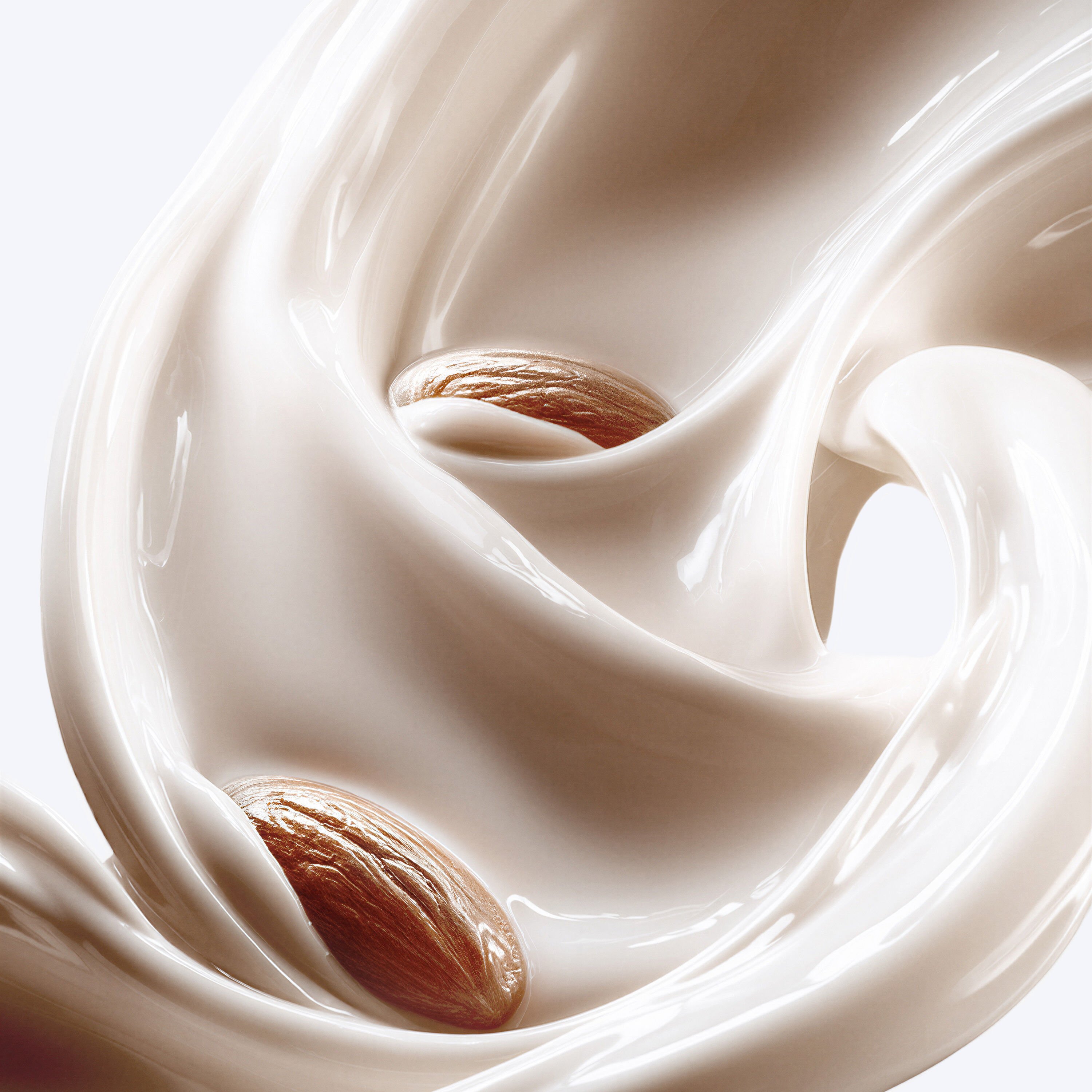 Lait d'amande crémeux avec des tourbillons élégants et des éclats de noix, évoquant une expérience raffinée.