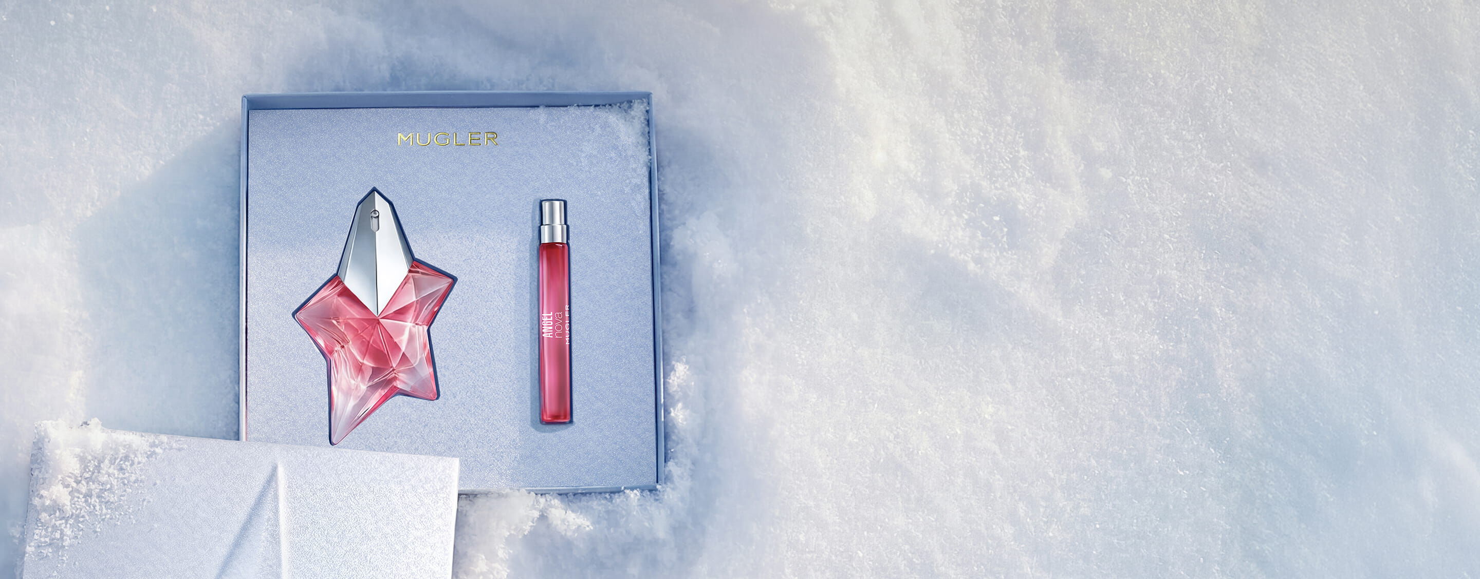 Un coffret cadeau Mugler bleu glacier, ouvert et texturé, scintillant sur un fond de neige, dévoilant un coffret cadeau Angel Nova Eau de Parfum de 50 ml.'