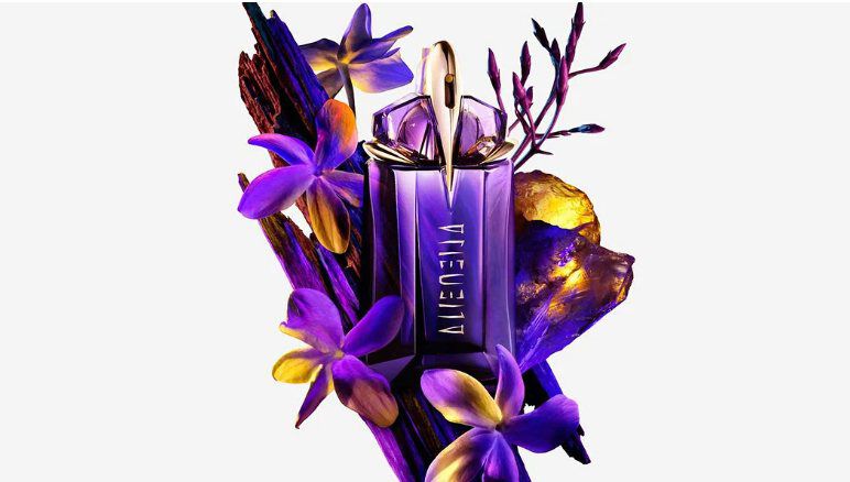 un flacon de parfum vert mugler entouré de fleurs de jasmin et de bois