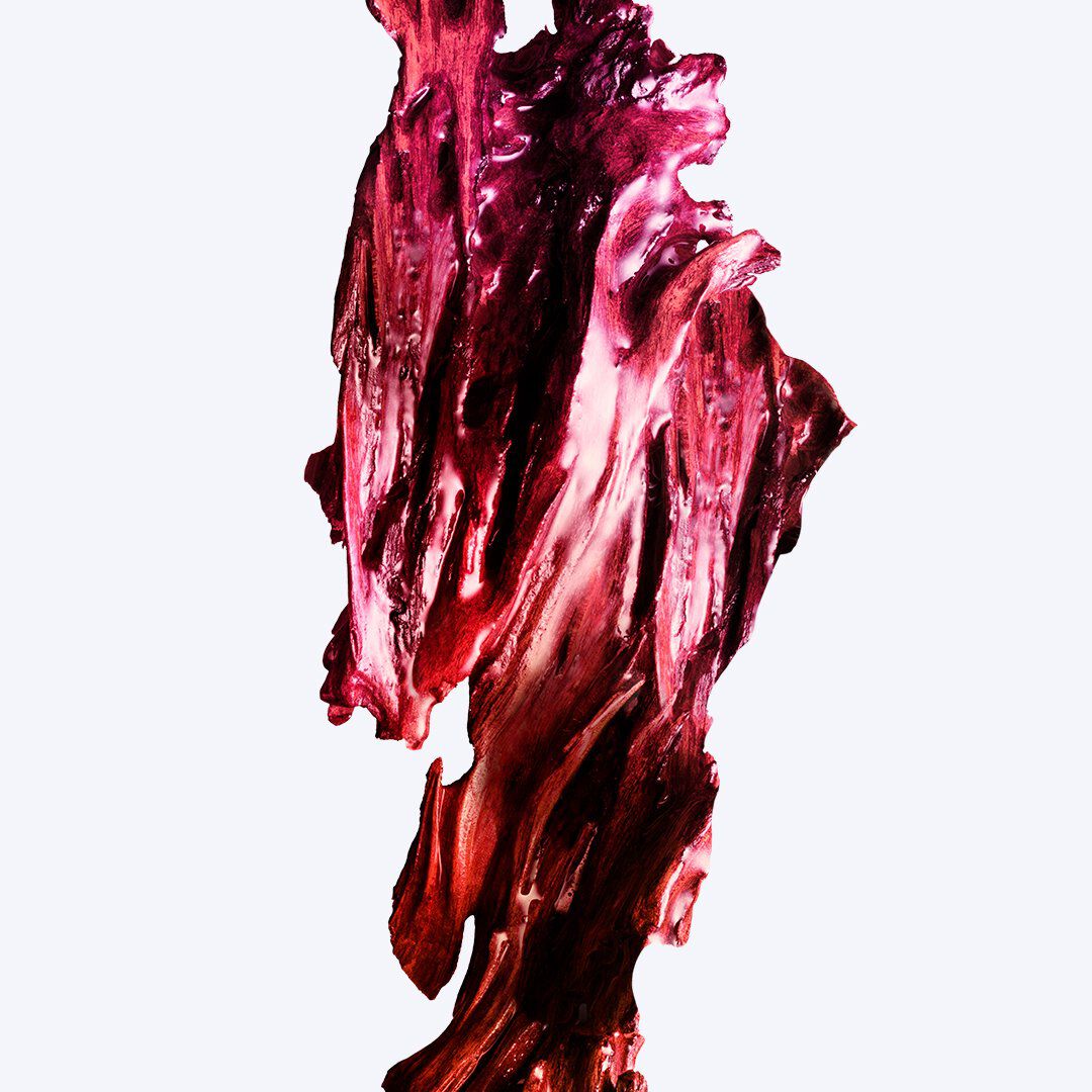 Tache abstraite et diffuse d un ingrédient de parfum aux teintes pourpre foncé et framboise sur un fond bleu pâle
