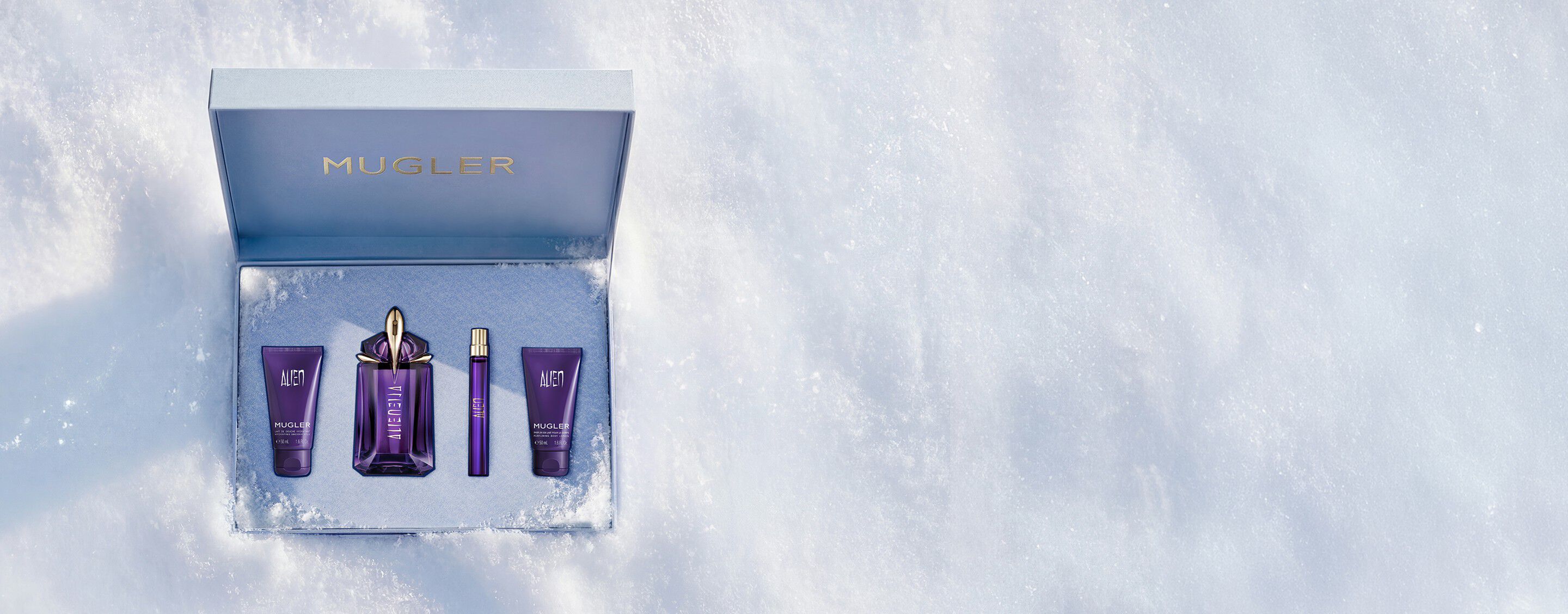 Un coffret cadeau Mugler bleu glacier, ouvert et texturé, scintillant sur un fond de neige, dévoilant un coffret cadeau de luxe contenant l eau de parfum Alien de 60 ml.