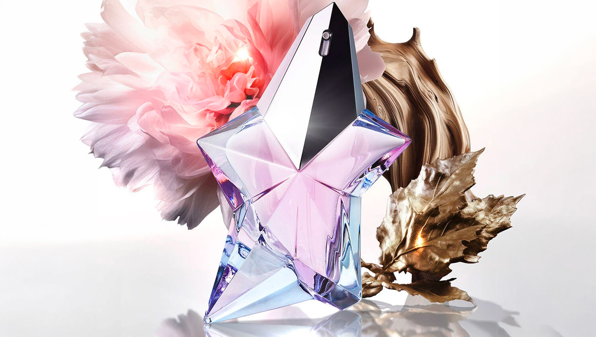 Flacon en forme d'étoile de l'eau de toilette Mugler Angel, entouré d'une pivoine rose et de notes boisées dorées, mettant en valeur les notes florales et chaudes caractéristiques de ce parfum.
