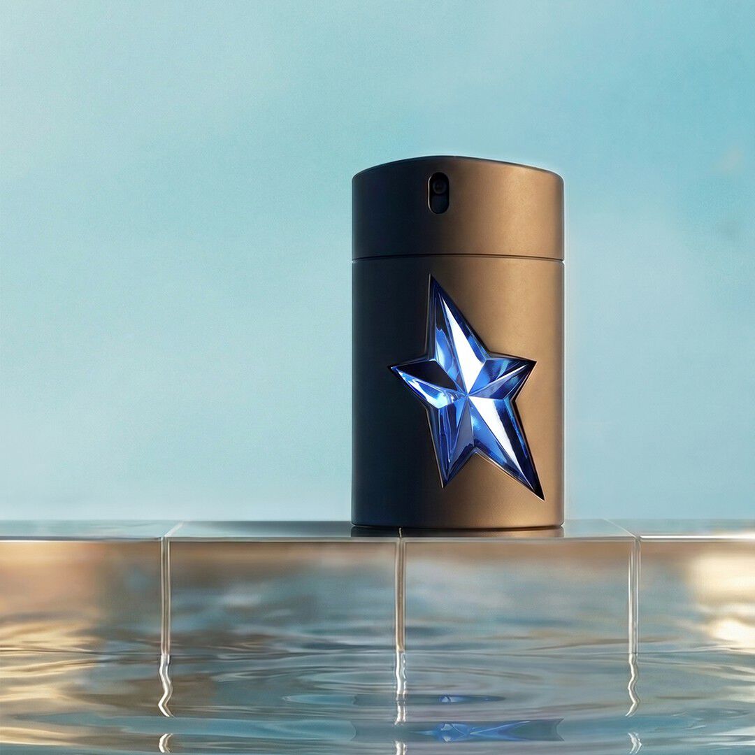 Flacon de l eau de toilette Mugler A Men, orné d une étoile bleue à facettes posée sur un rebord carrelé au-dessus d un bassin aux reflets miroitants.