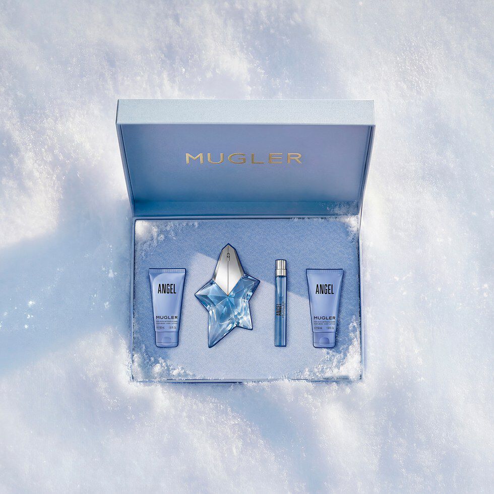 An open, textured ice-blue glistening Mugler gift set resting on snow, revealing an angel eau de parfum 50ml luxury gift set