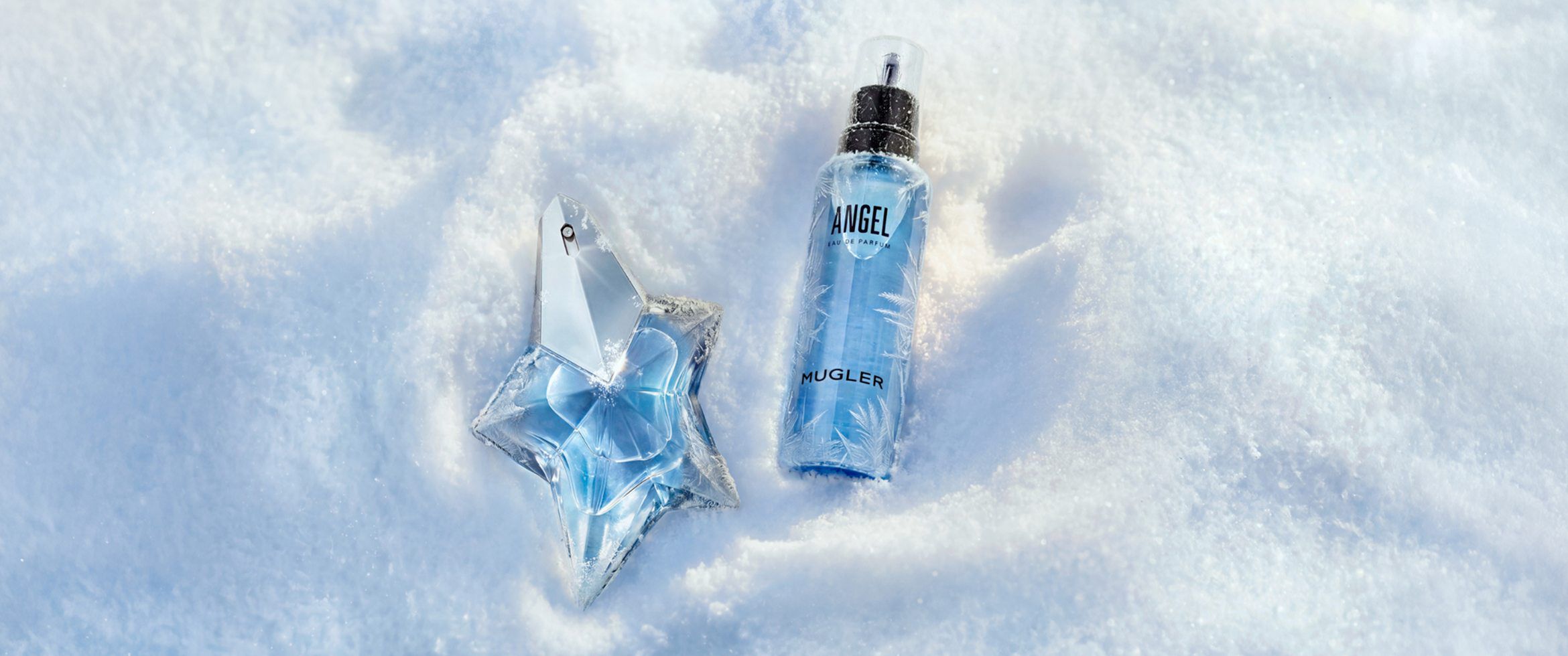Le parfum Mugler Angel eau de parfum et son flacon de recharge bleu assorti, dans un décor hivernal enneigé.