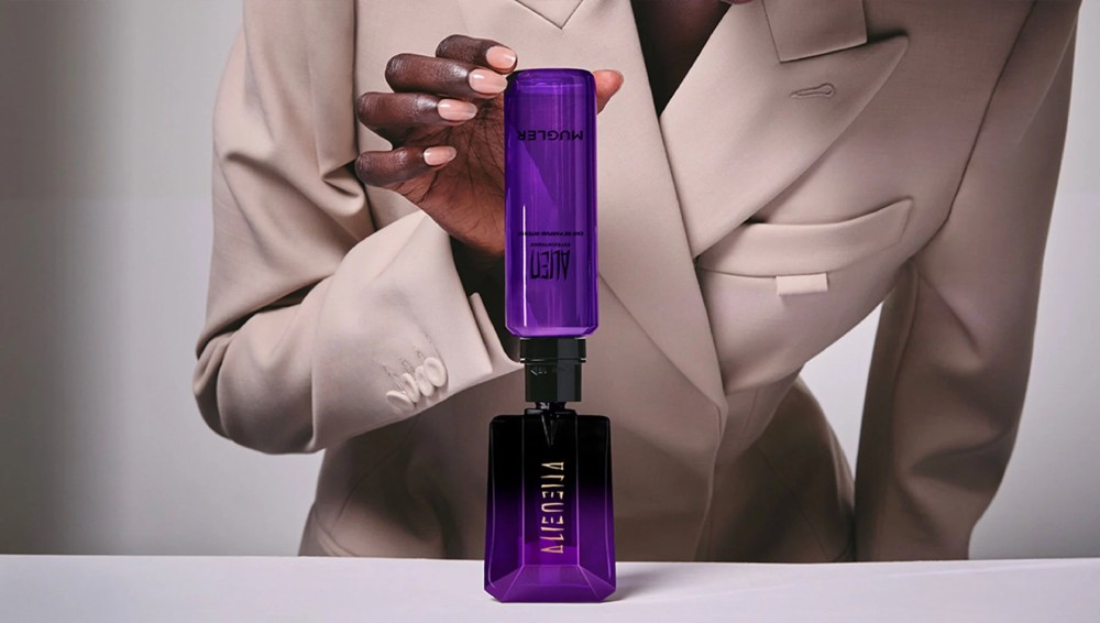 Flacon de parfum ALIEN de Mugler, violet, avec un fond flou aux nuances de violet et de rose.