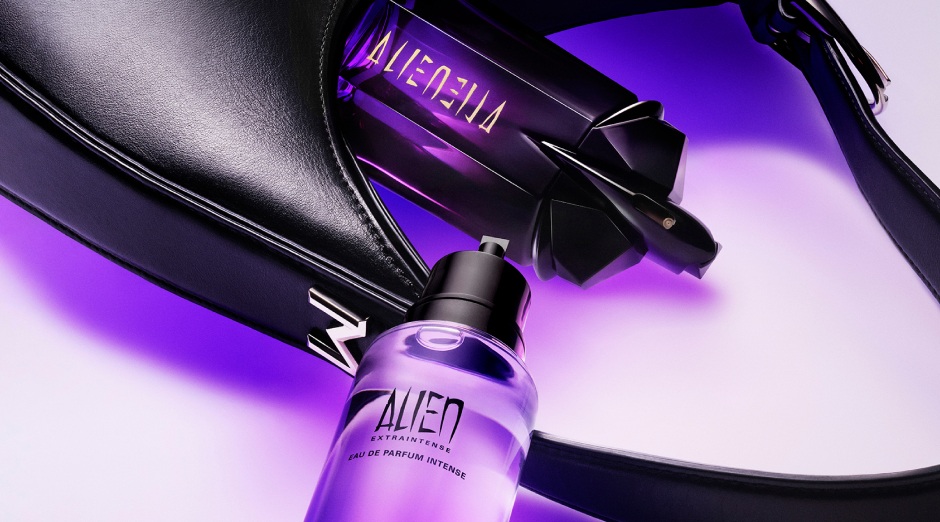 Flacon de parfum Alien et parfum intense sur un fond violet, à côté d'un sac noir élégant.