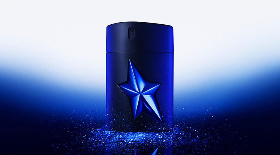Flacon de parfum noir avec étoile bleue, sur fond dégradé. Évoque élégance et mystère.