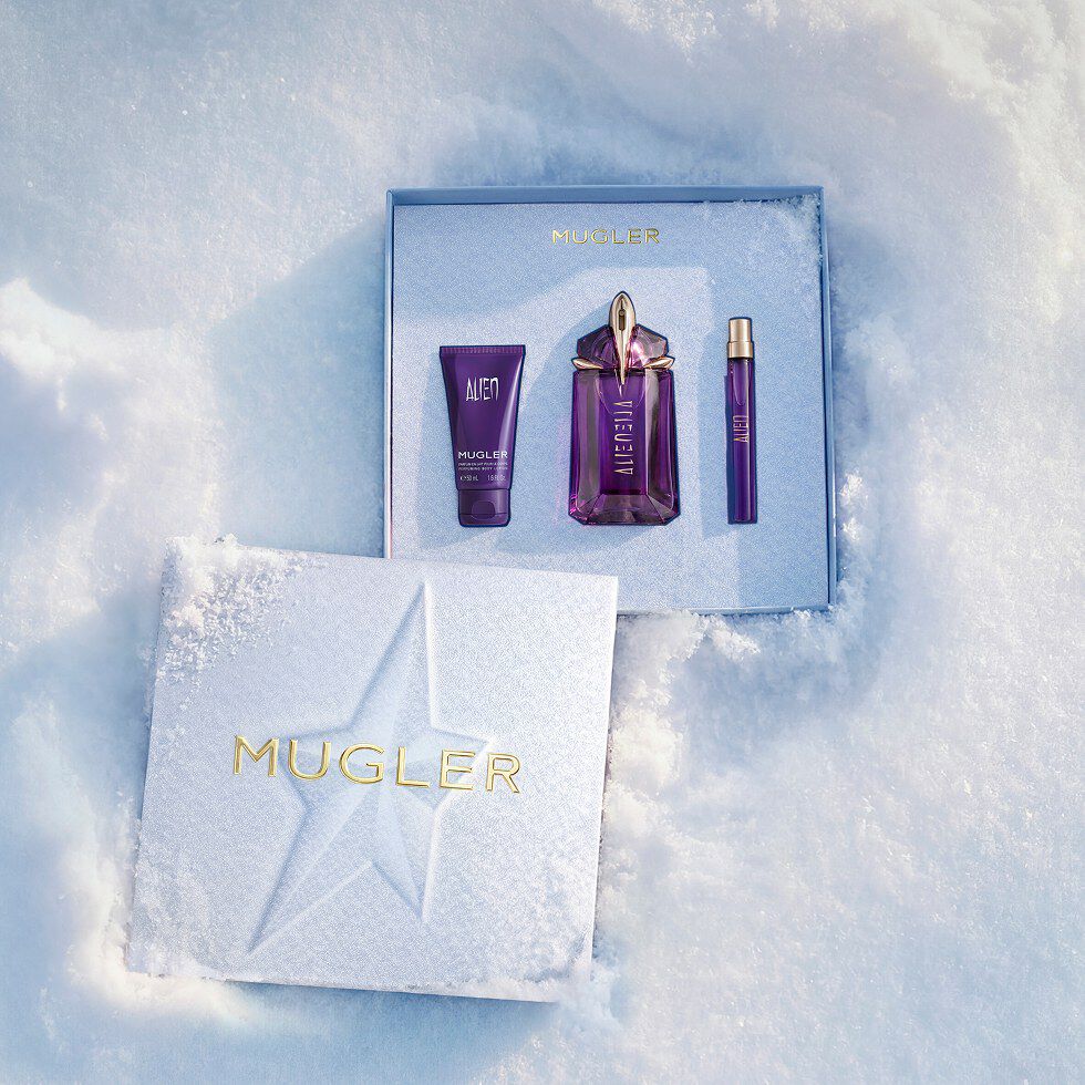 Un coffret cadeau Mugler bleu glacier, ouvert, texturé et scintillant, posé sur de la neige, dévoilant un coffret cadeau d eau de parfum Alien de 60 ml