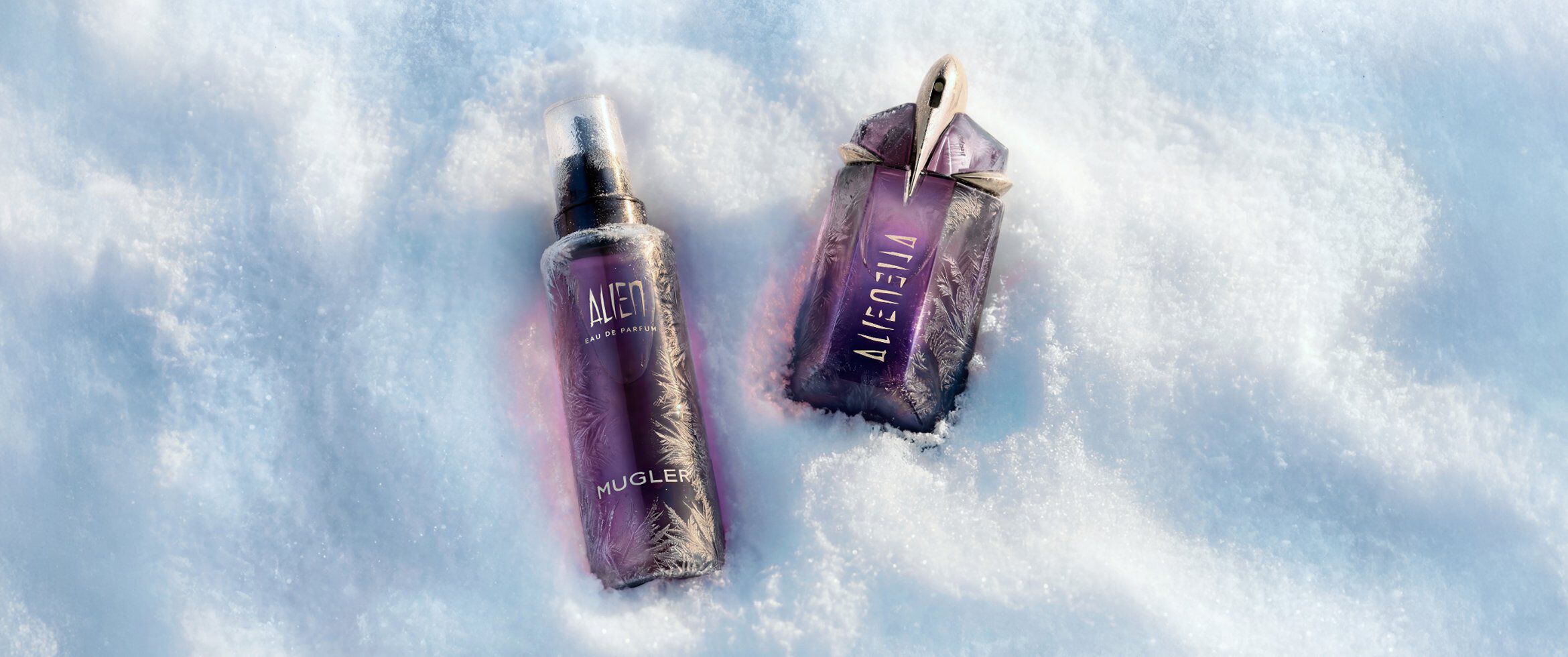 Le parfum Alien d'Mugler, en version eau de parfum violette, et son flacon de recharge assorti, nichés dans la neige.
