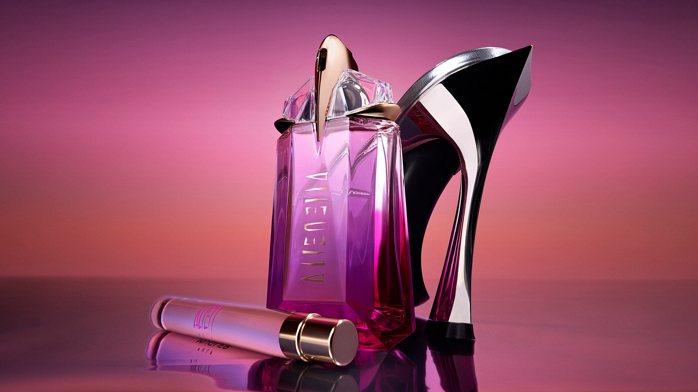 un parfum alien rose et son format voyage posés devant un escarpin sur un fond rose